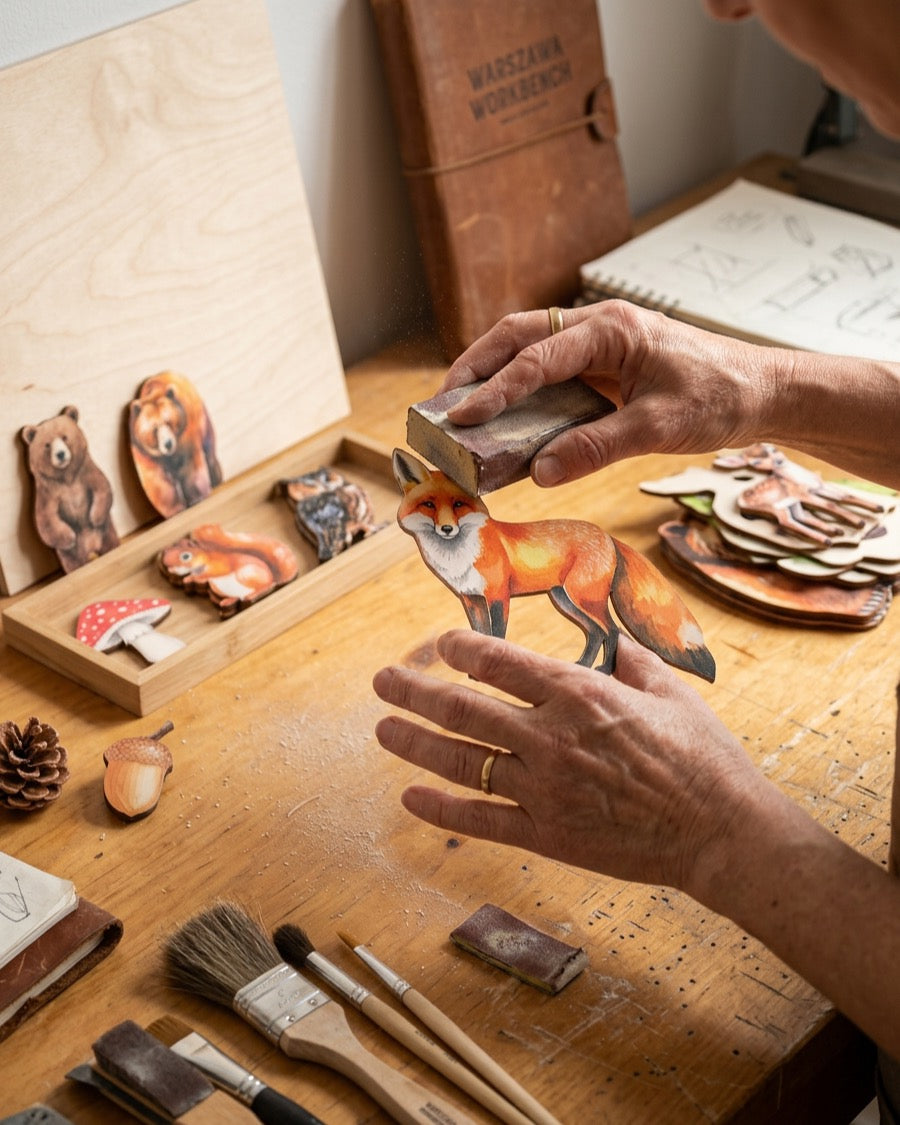 Hands finishing a birch fox in the Warsaw workshop