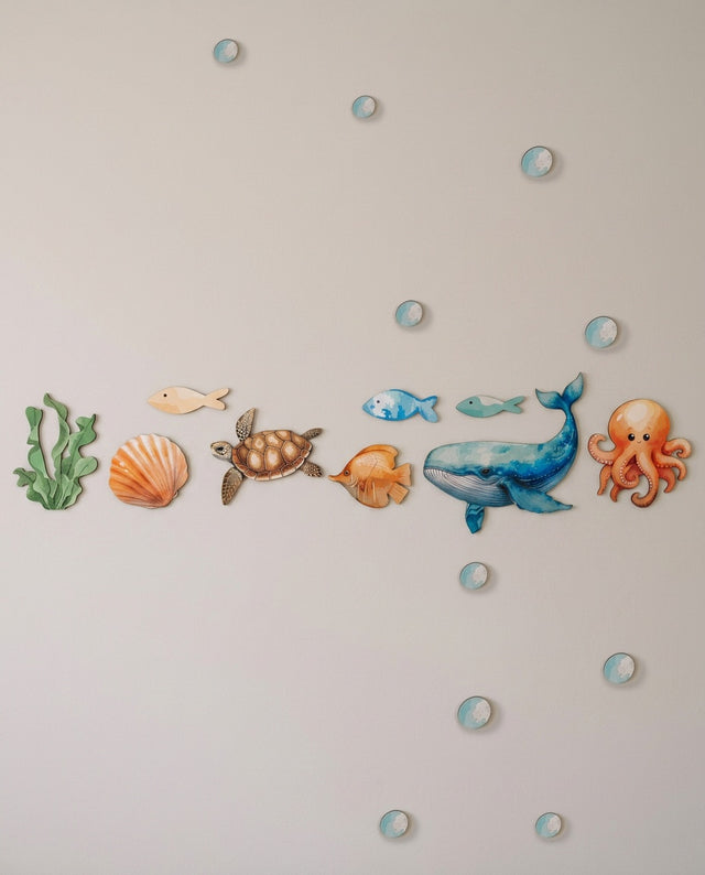 Ocean wooden wall art set arranged as along the reef — Fish and seaweed lined across a shelf like a coral line.